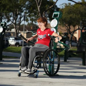 A woman in a wheelchair exercising on the Accessible Tricep Press (adjustable resistance)