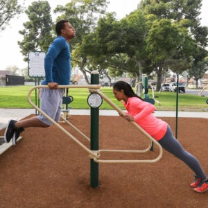 A man and woman using the dips and push up station