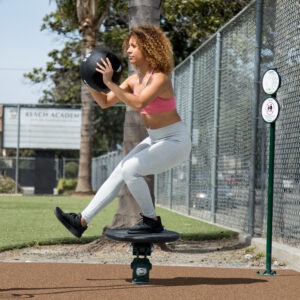 A woman doing a pistol squat on a balance plate