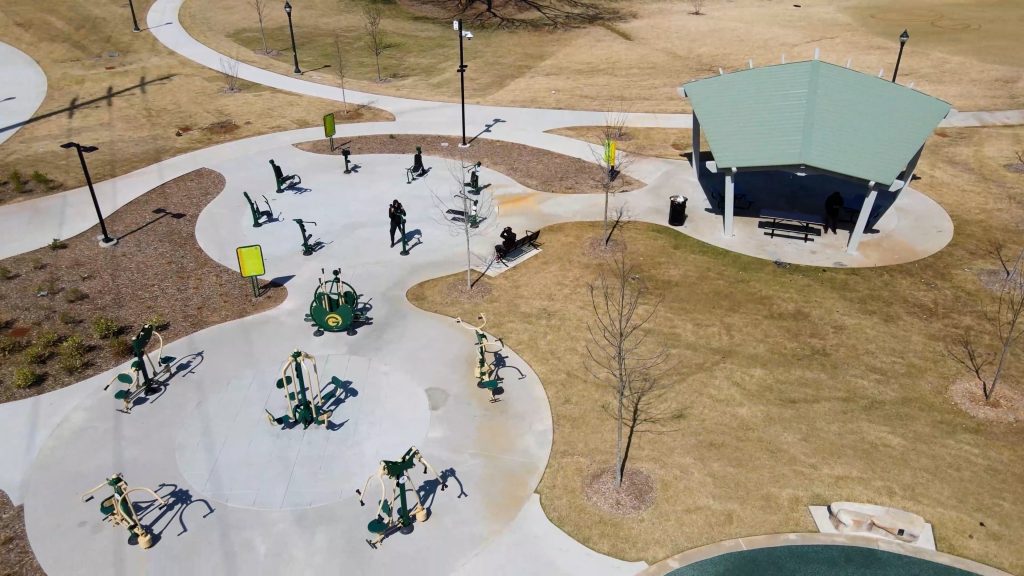 A fitness area at a park with grass trees a gazebo surrounding it