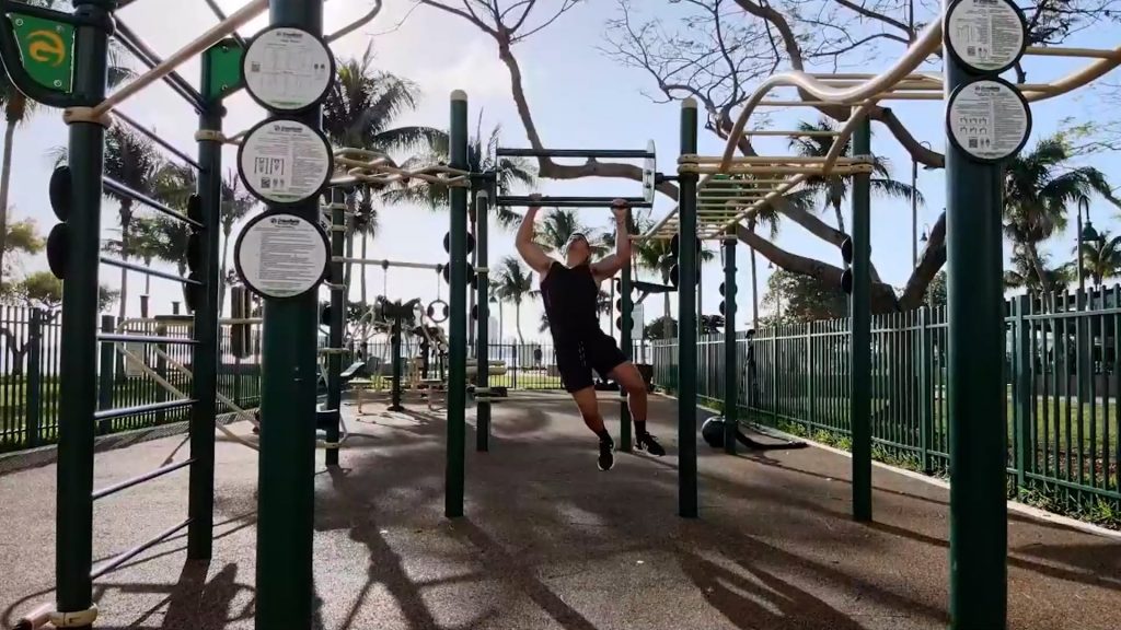 A man exercising on the Rotating Pull-Up Wheel on the custom rig at Margaret Pace Park