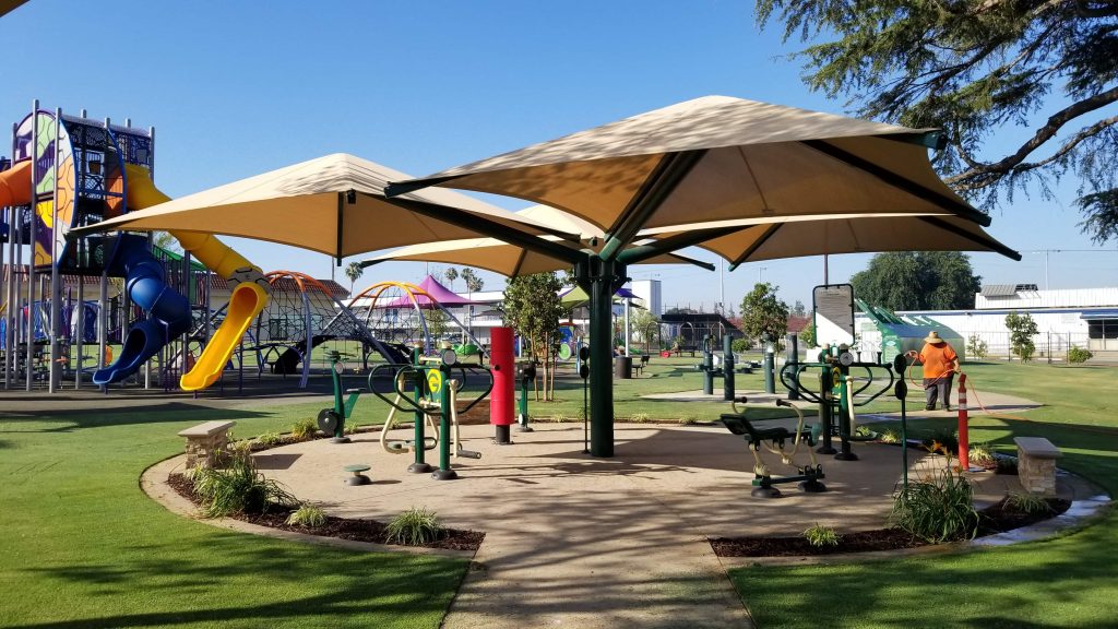 An outdoor workout area with a playground in the background