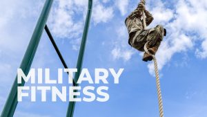 A man in army fatigues climbing the Rope Climb, in the bottom left written in text it says: Military Fitness