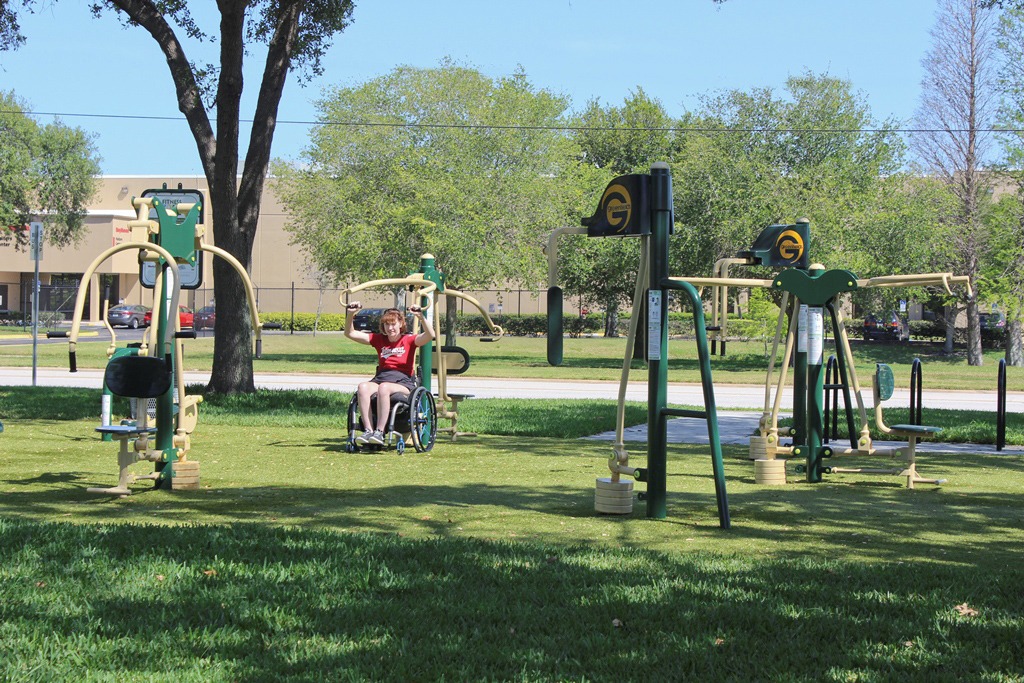 A young girl uses outdoor exercise equipment to exercise in a park