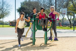 Three women and one men exercising on 4-Person Pendulum, Abs, & Dip Station
